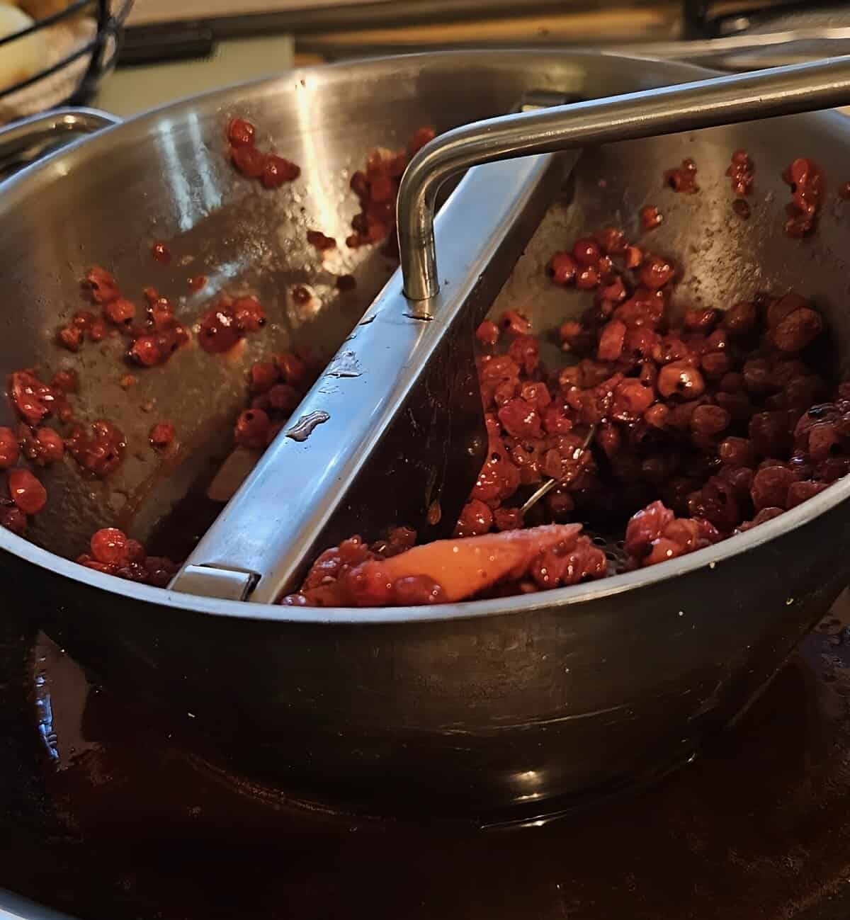 food mill shown in action of pressing currant glaze mixture