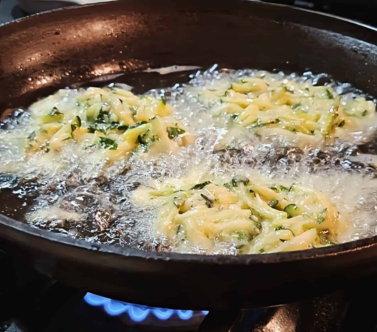 zucchini fritters frying in oil