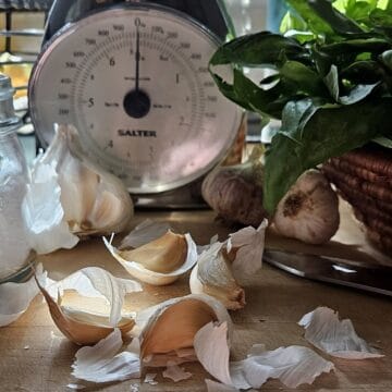 garlic cloves and basil with food scale in the background