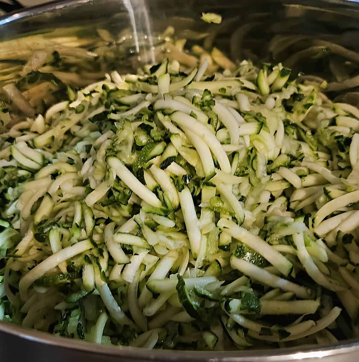 shredded zucchini in a metal mixing bowl