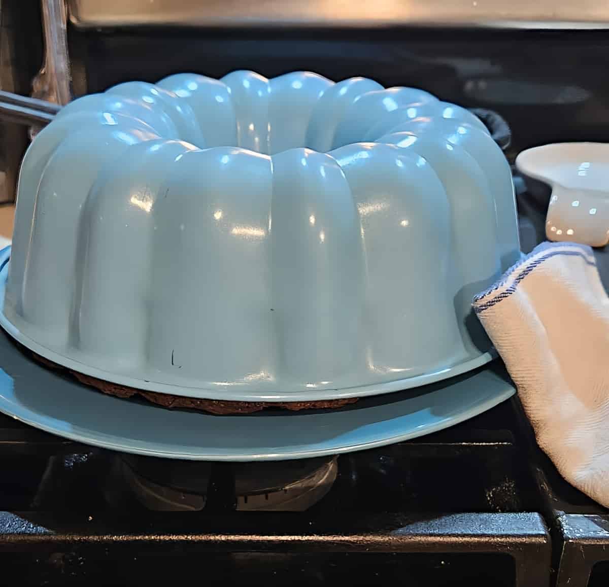 bundt pan on top of plate, being lifted to reveal zucchini bread inside
