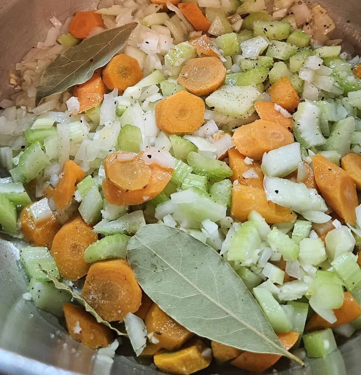 small dice yellow onion, bay leaves, sliced carrot, small diced celery, minced garlic, coarse salt, and ground black pepper in a mixing bowl