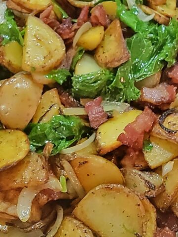 close up of finished breakfast potatoes, with onions, kale, and bacon pieces