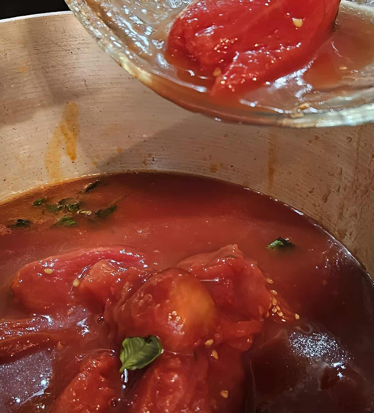 adding tomatoes to saucepan