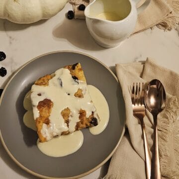 plated bread pudding with crème anglaise sauce, linen napkins, fork and spoon