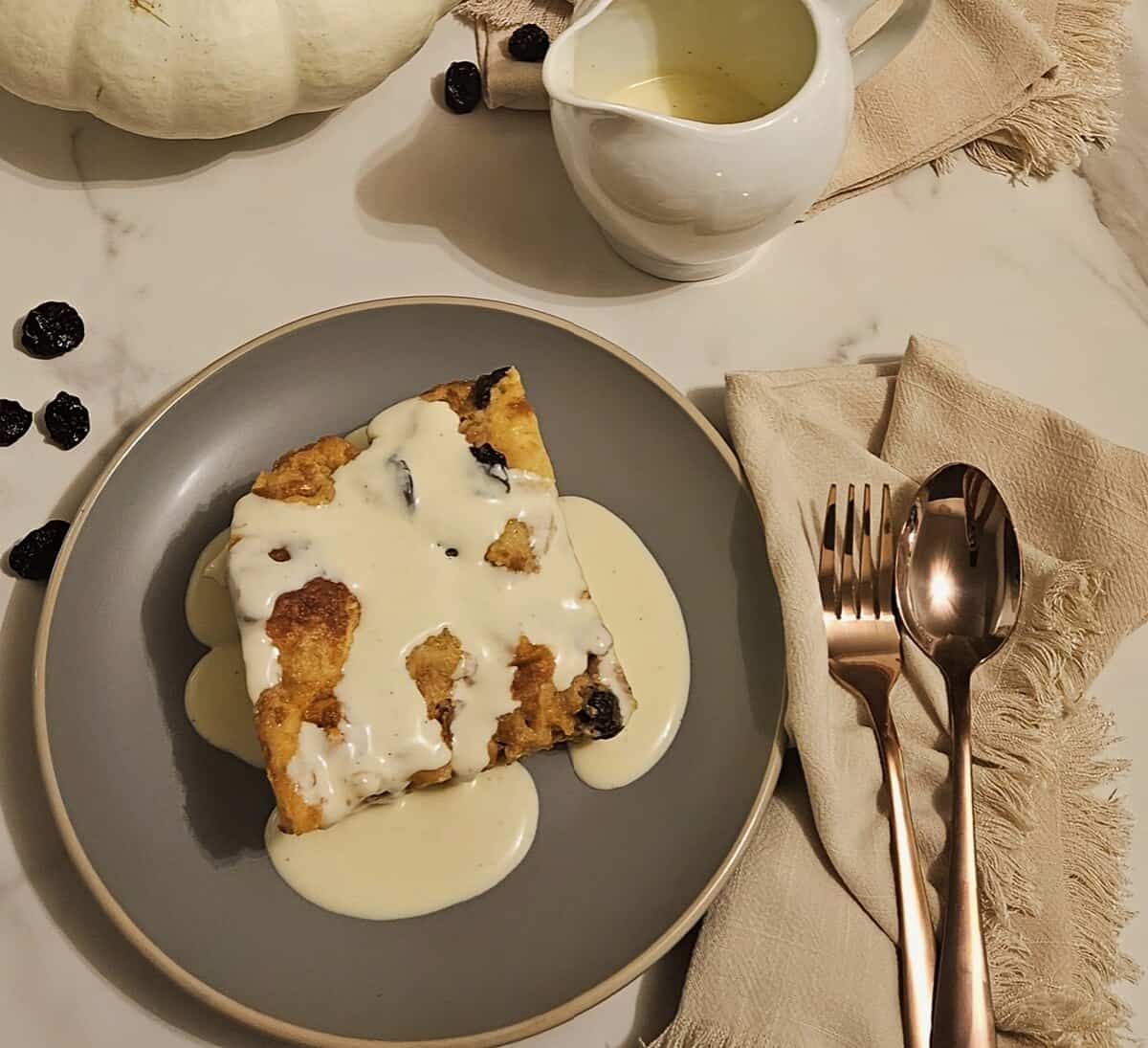 plated bread pudding with crème anglaise sauce, linen napkins, fork and spoon