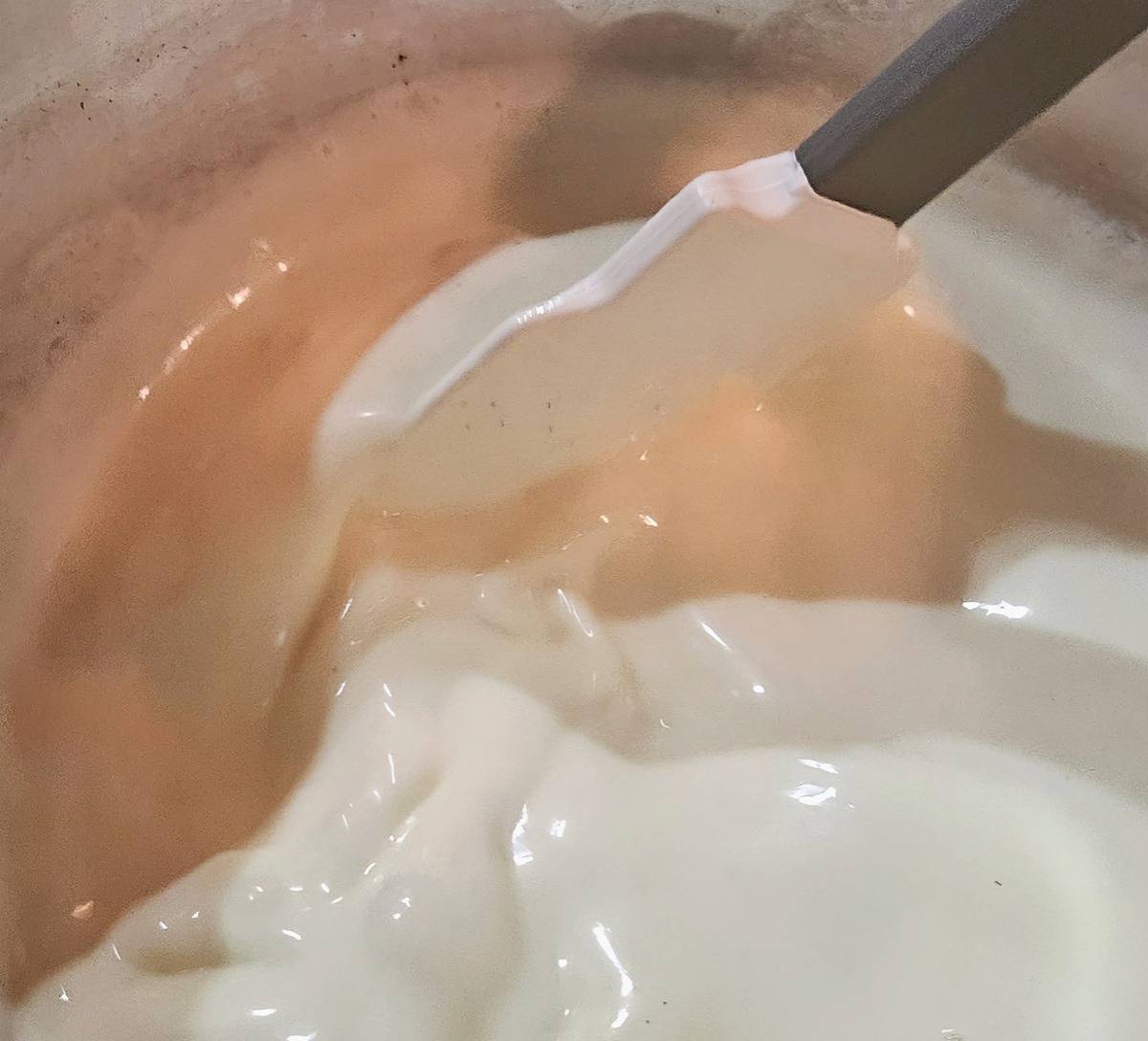 cream sauce being stirred in a saucepan with a spatula