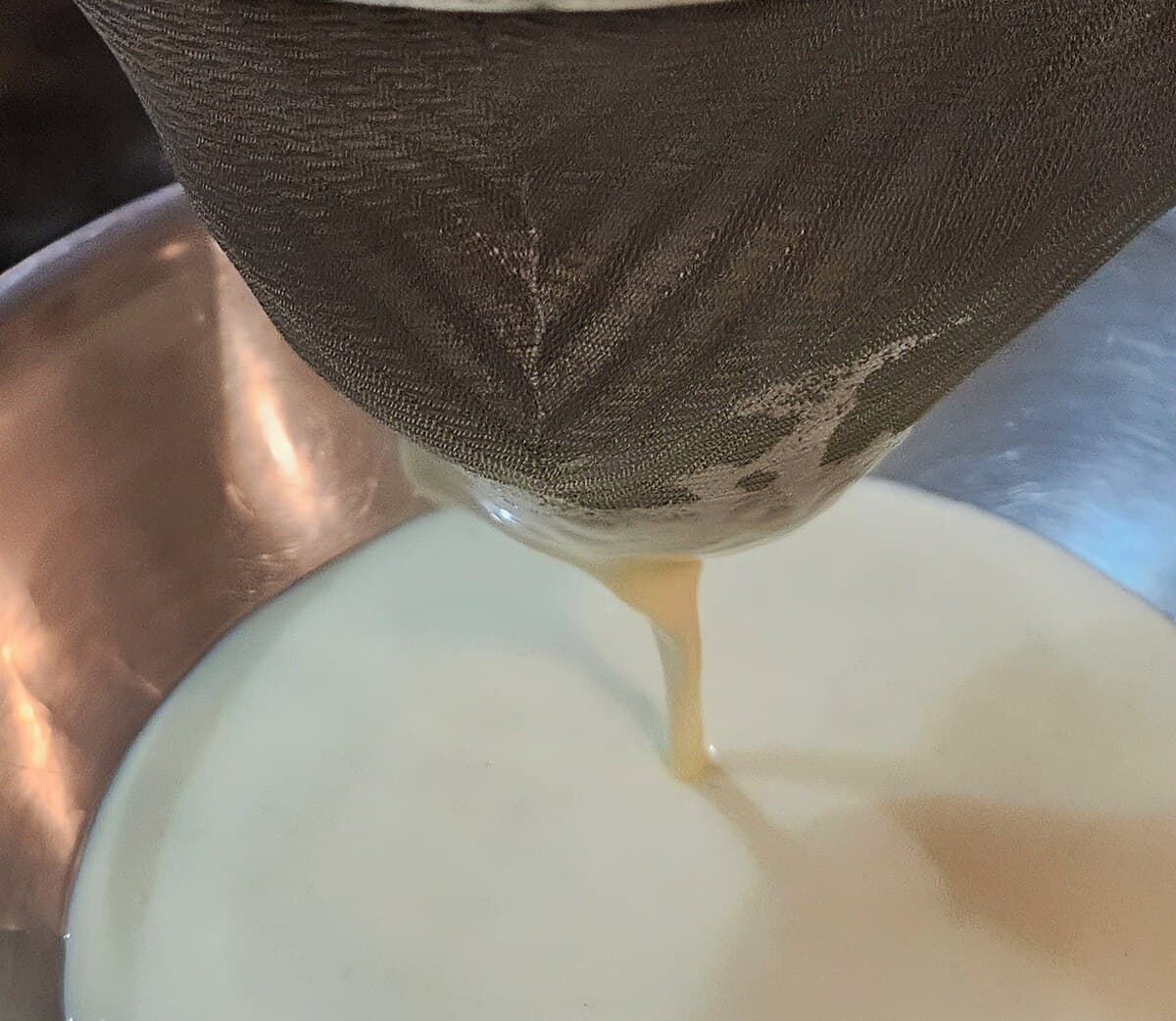 cream being poured through a conical seive