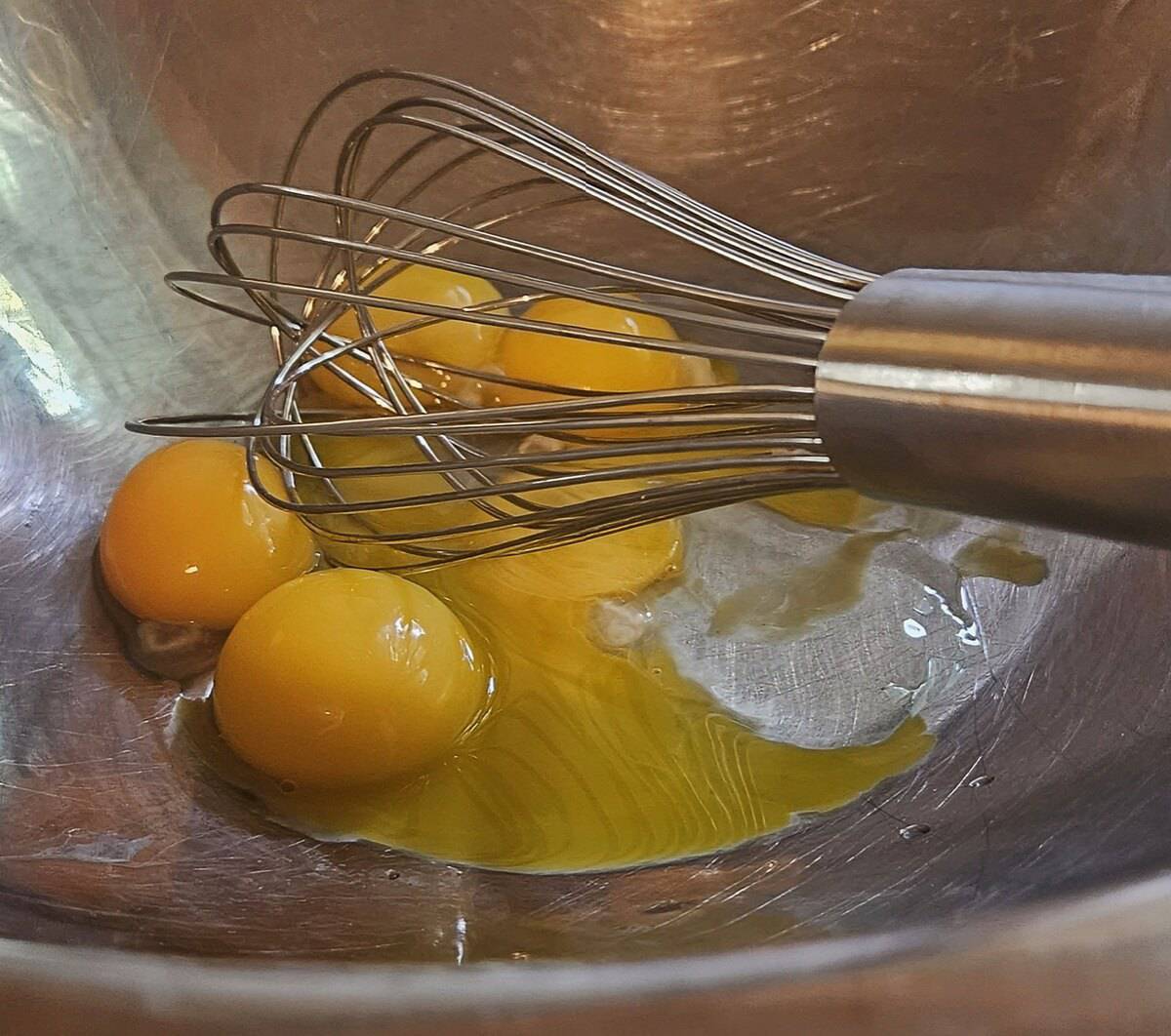 eggs in a mixing bowl with a wire whip resting in them