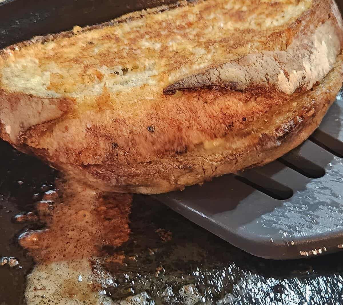 finished crusty and crisp grilled cheese sandwich being lifted from the pan with a spatula