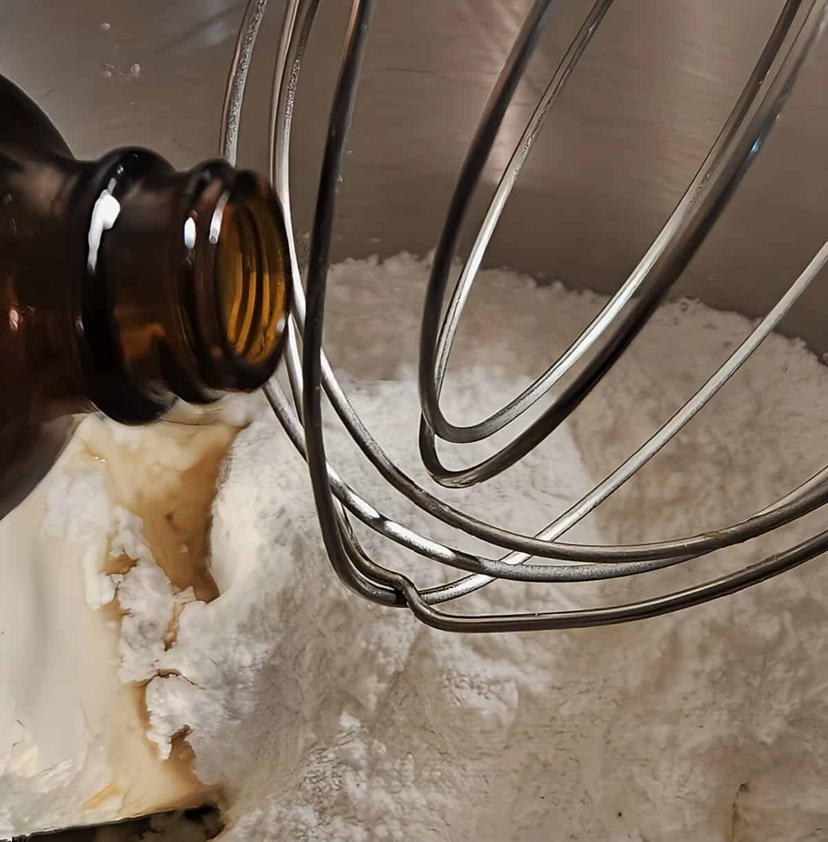 assembly of cream cheese filling for pumpkin whoopie pies; inside of mixer bowl with powdered sugar, cream cheese, butter, and vanilla extract being poured in