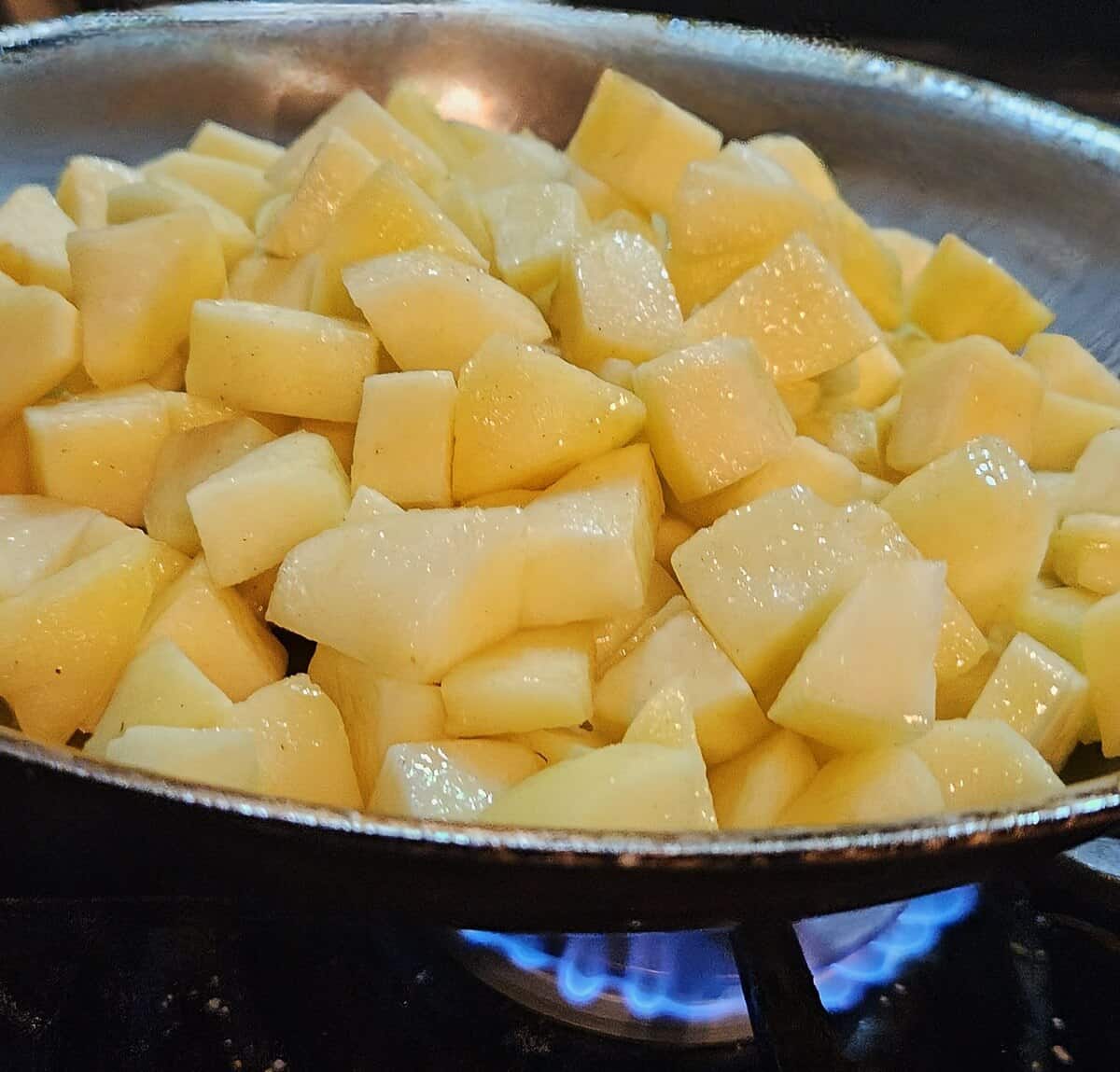 chunks of apple in a skillet cooking over a high flame