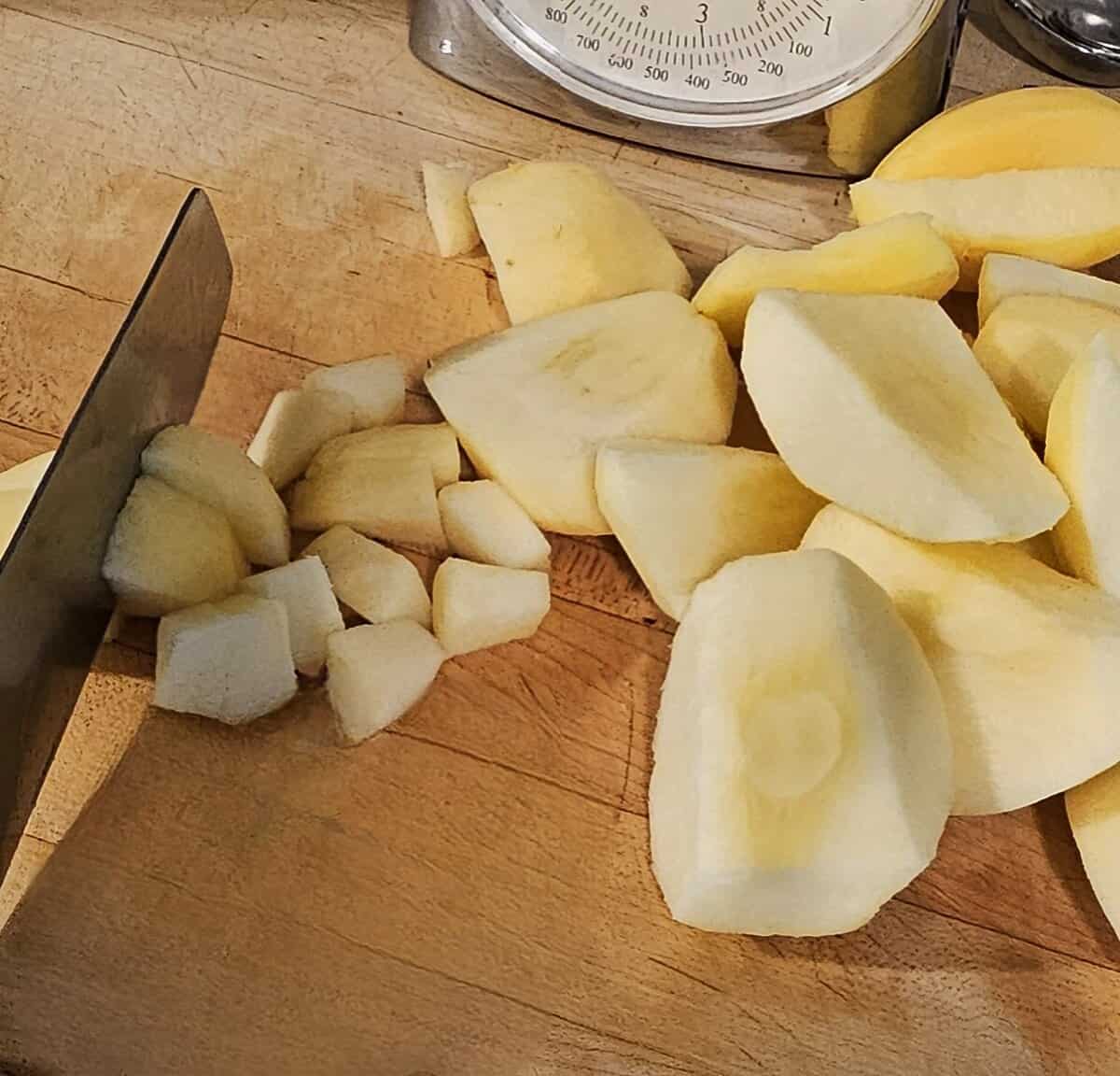 cut and cored apple segments being cut into smaller, 1 inch sized pieces