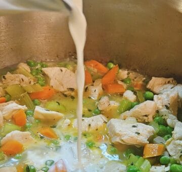 half and half being poured into pot to combine with chicken cobbler filling.