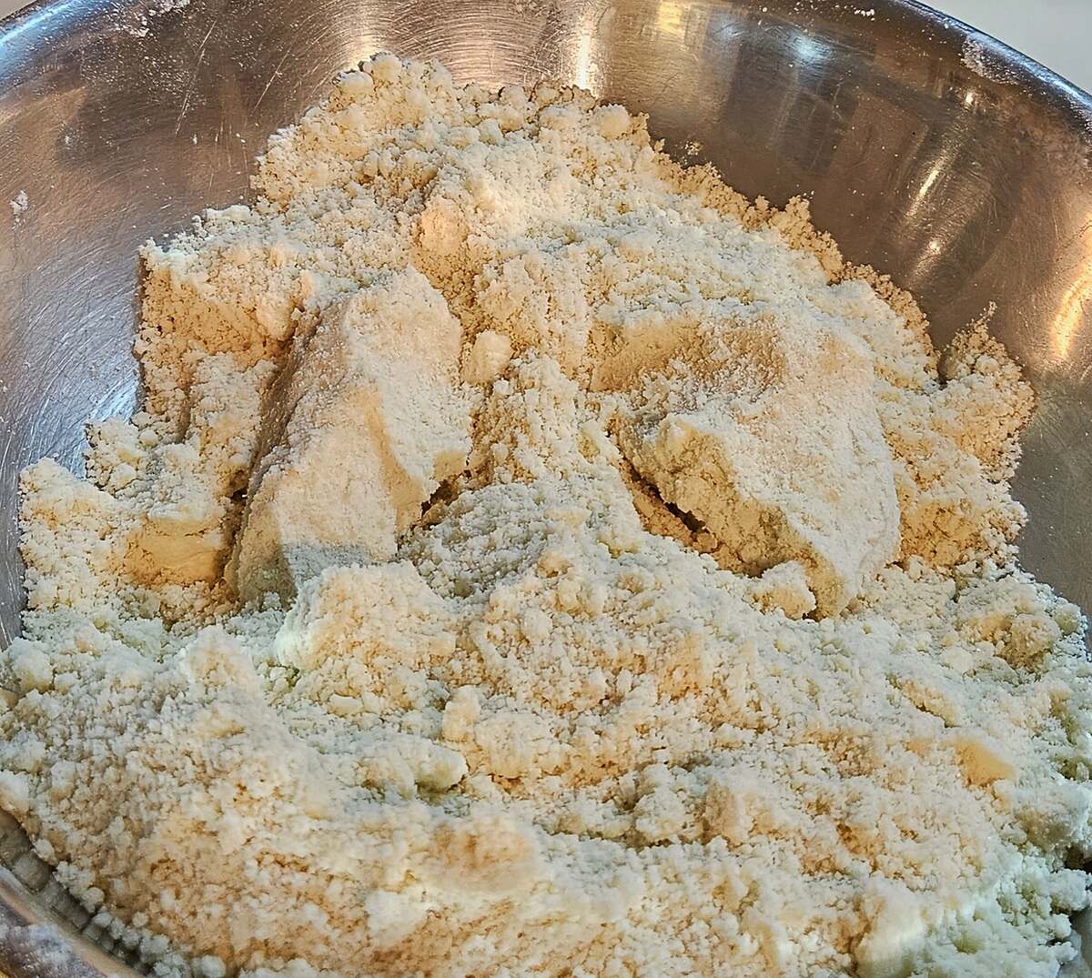 flour and butter mixture in a mixing bowl, handful sized clumps to how proper consistency