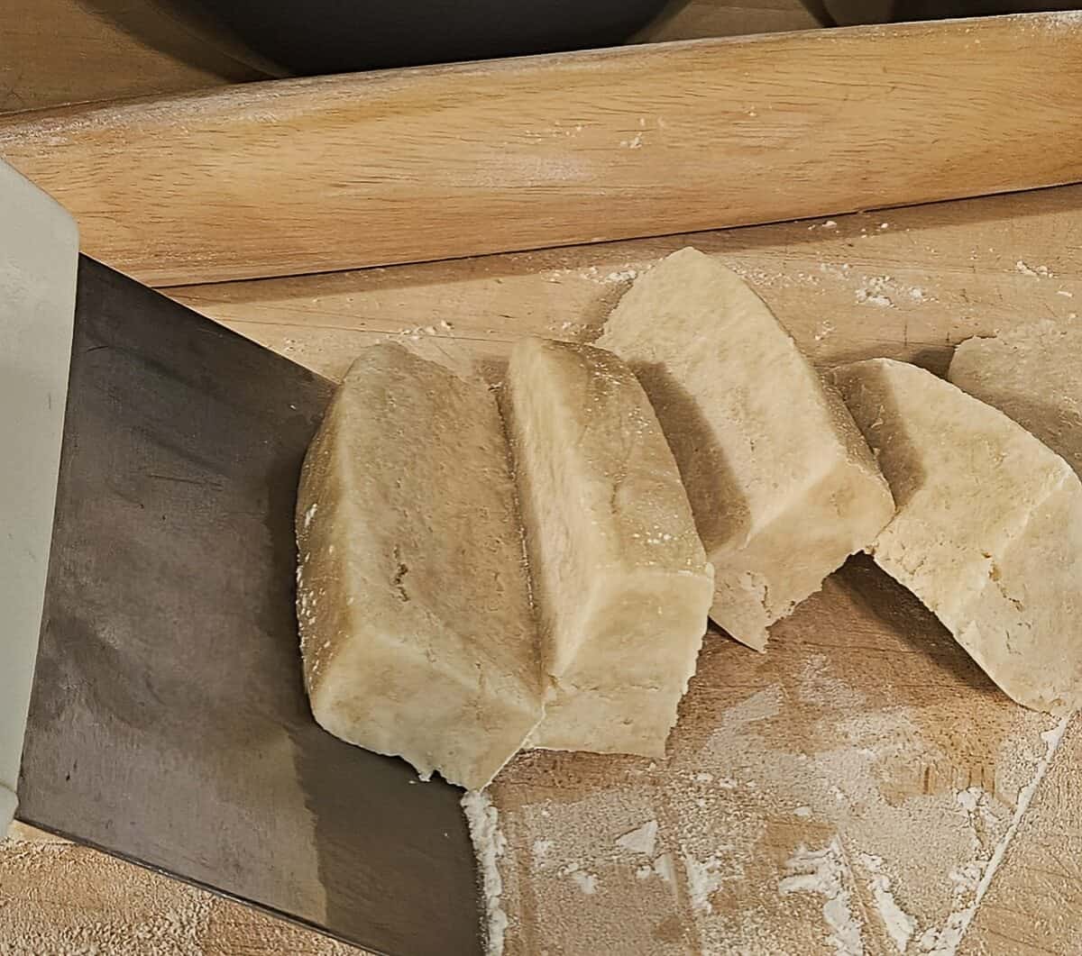 pie dough cut into small rectangular pieces with dough blade on floured cutting board