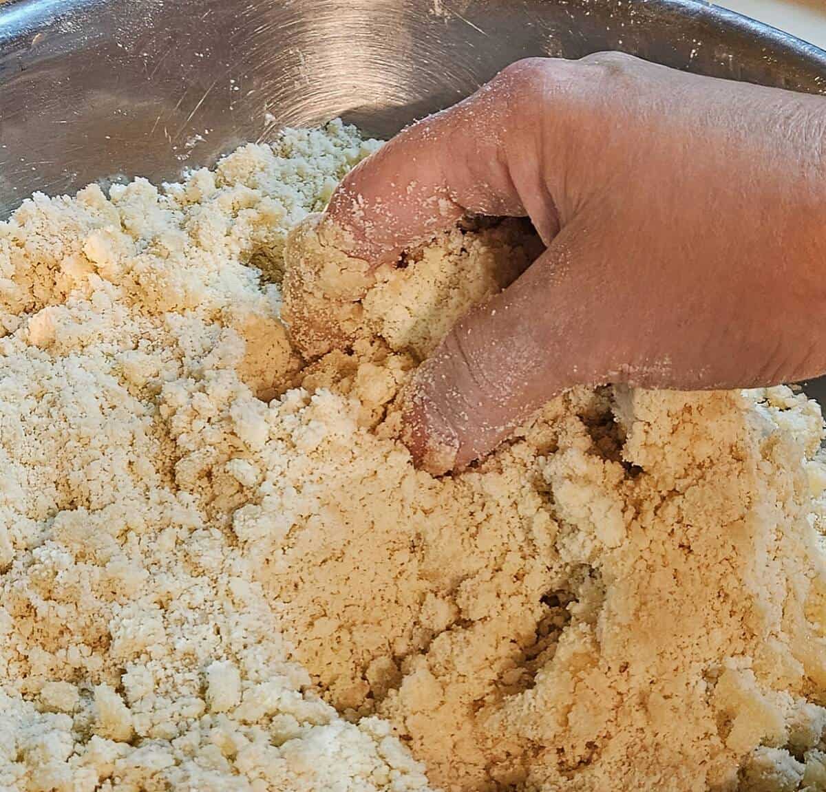 flour and butter mixture being mixed by hand after adding a small amount of water