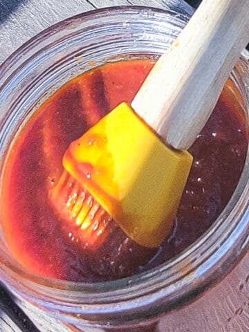 barbecue sauce in a mason jar with a silicon brush resting in it