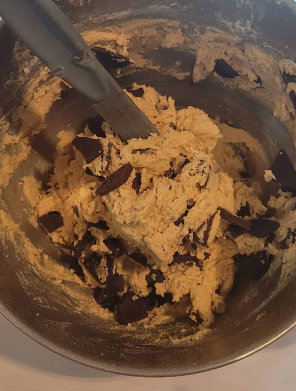 chocolate chunk cookie dough, folding in chunks of chocolate into dough with rubber spatula