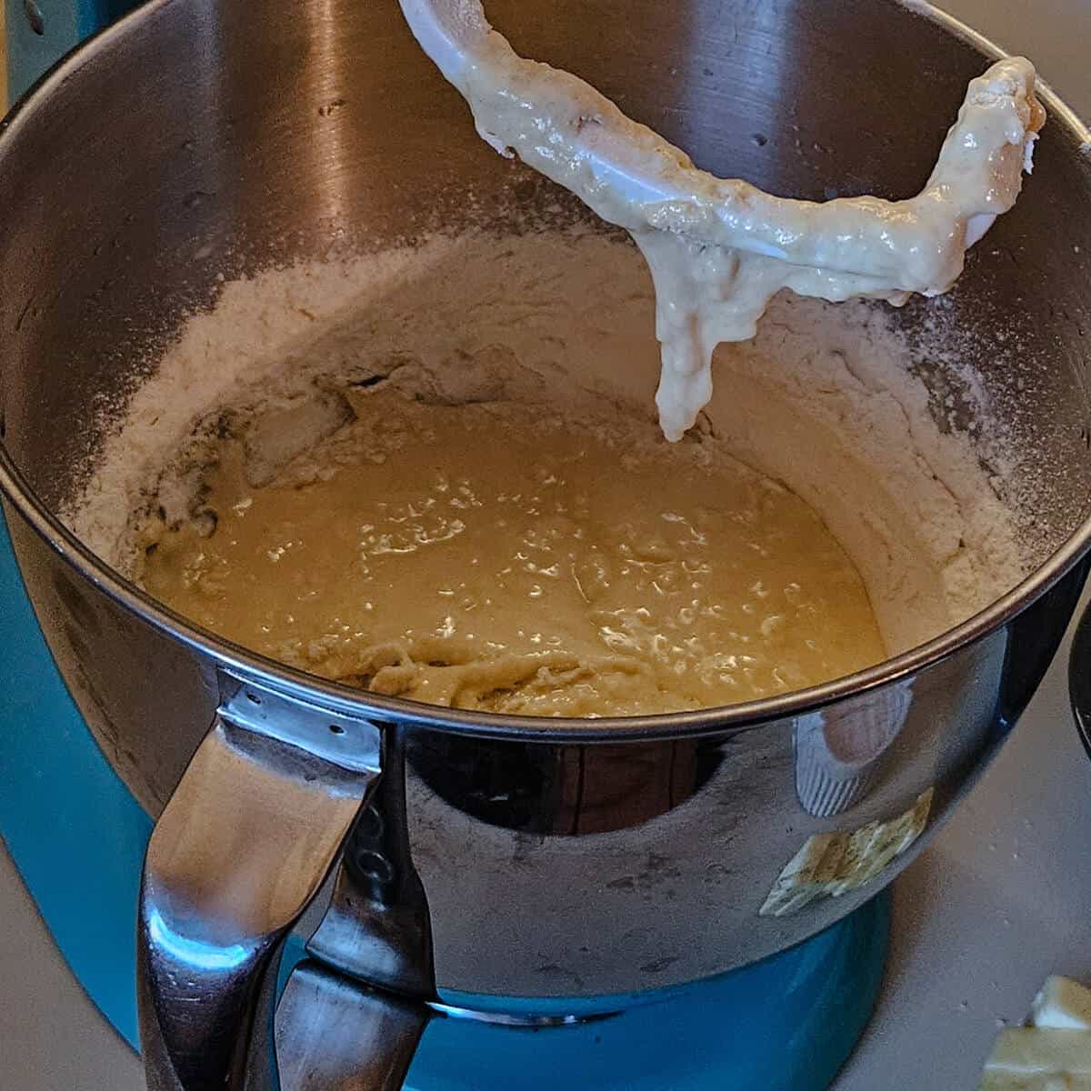 stand mixer interior, with wet batter and sry ingredients clinging to sides of bowl, dough hook dripping.