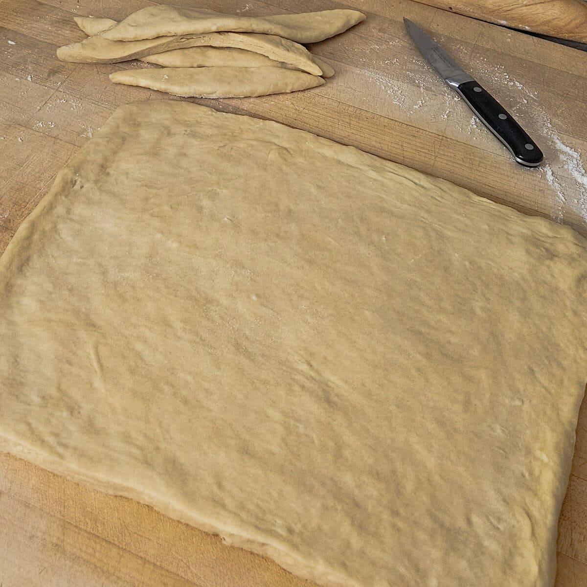 cinnamon roll dough rolled out and trimmed to a square
