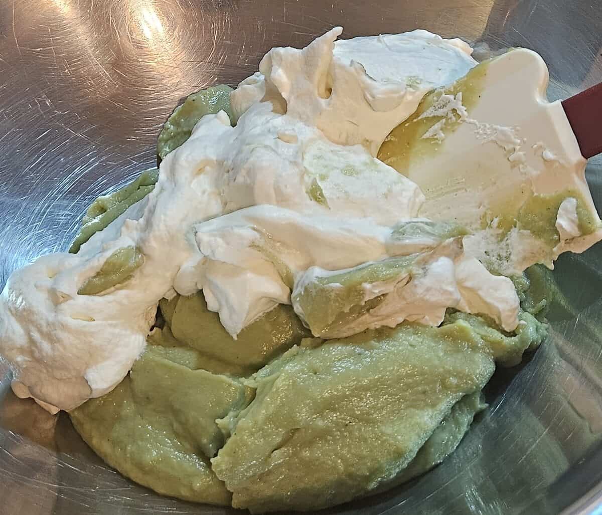 matcha cream puff pastry cream with whipped cream being folded into it with a rubber spatula.