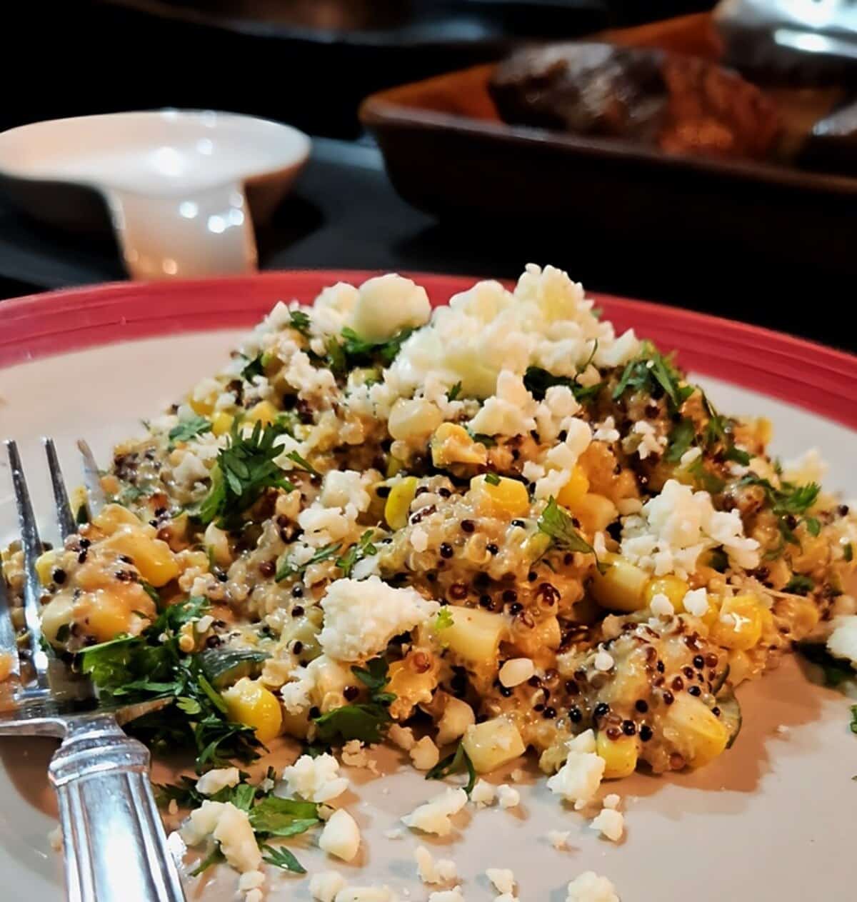 street corn style quinoa on a plate, cooked quinoa with roasted corn, cilantro, cotija cheese, and poblano chilies.