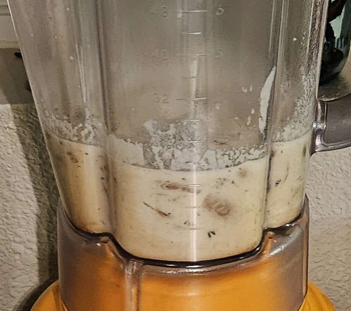 creamy mushroom asiago soup in a blender cup before being turned on to puree.