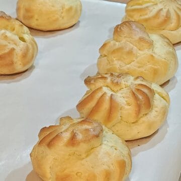 Finished pate choux baked to brown on parchment lined sheet pan