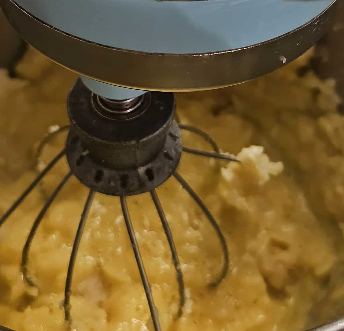 overhead view of a stand mixer showing the pate choux mixture consistency after adding eggs to it.