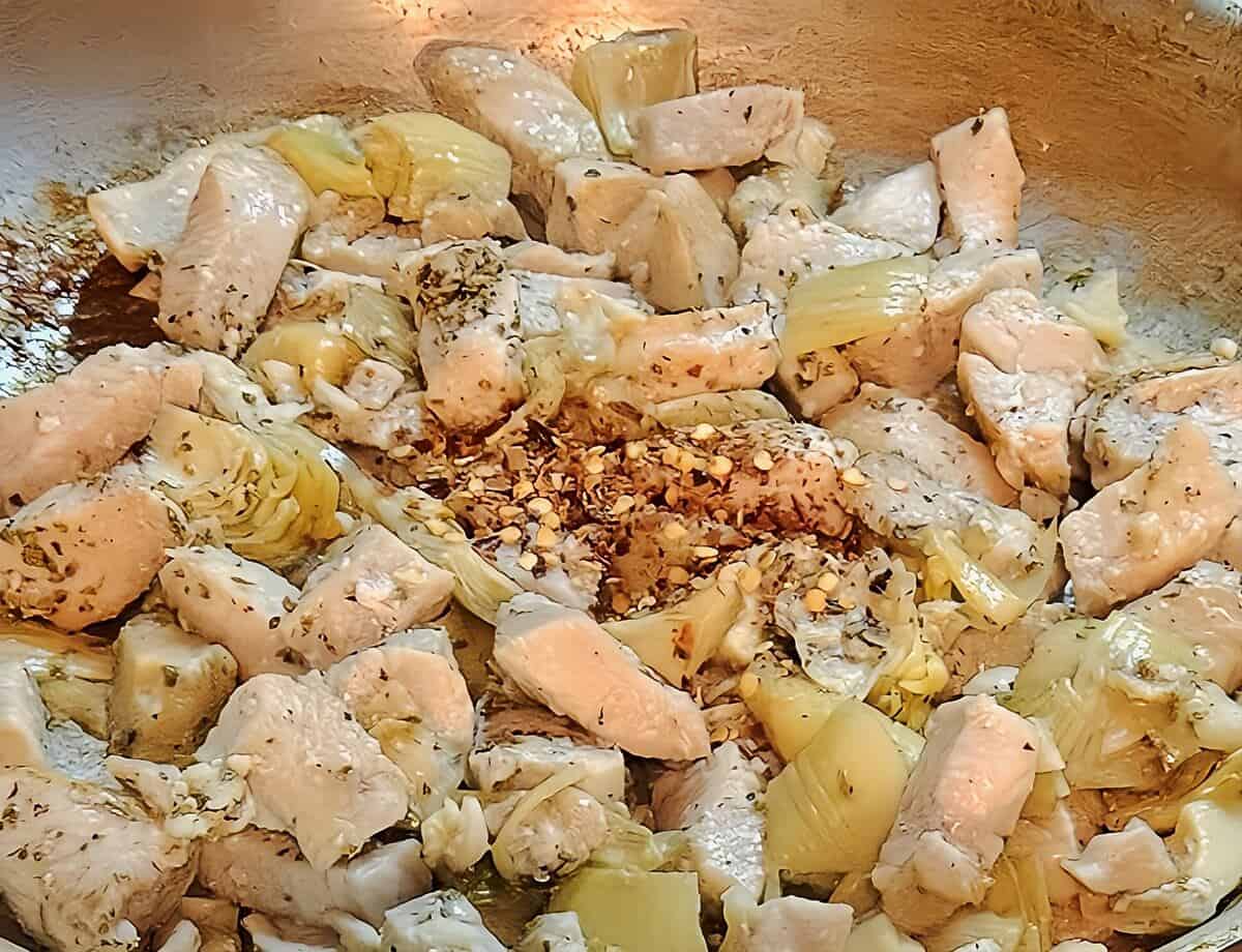 chicken pieces, artichoke hearts. dried red chili flakes, and dry herbs in a skillet cooking