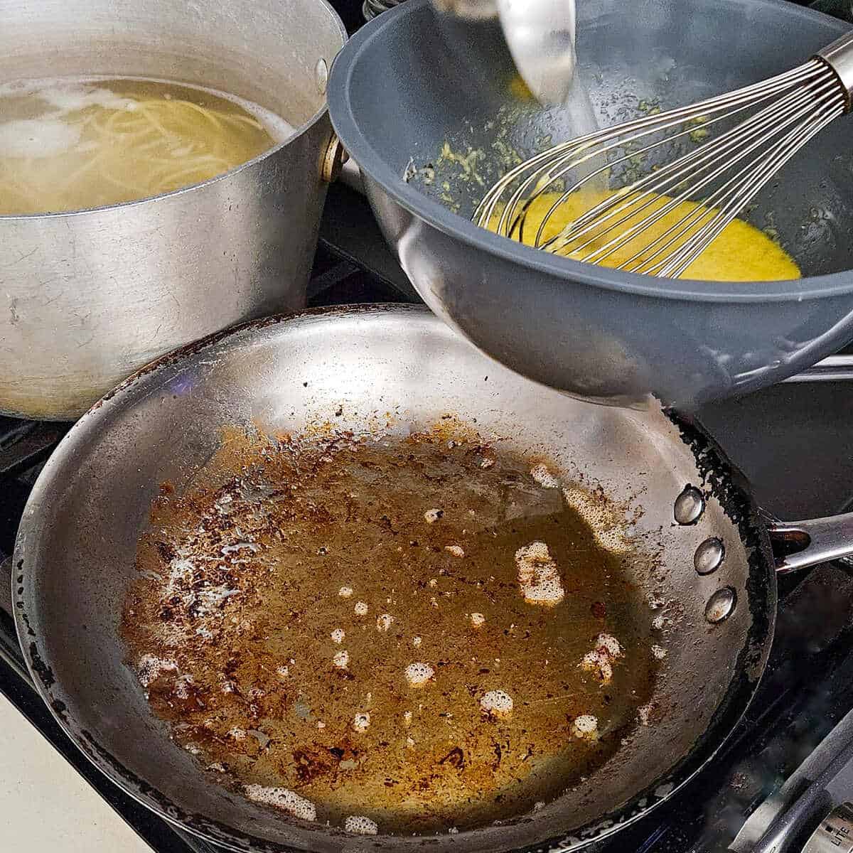 getting ready to add the egg and cheese mixture to the pan to create the pasta carbonara with mushrooms, the pasta is pictured in a pot of boiling water of to the side, ready to be added to the sauce