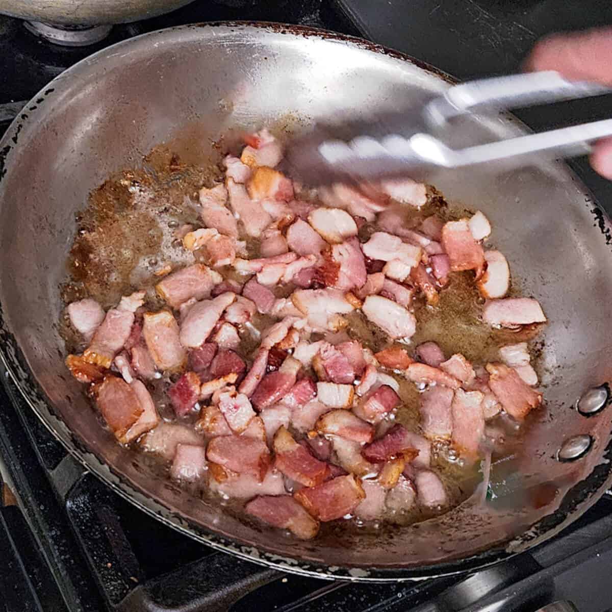 cooking the bacon pieces in a pan for the pasta carbonara with mushrooms