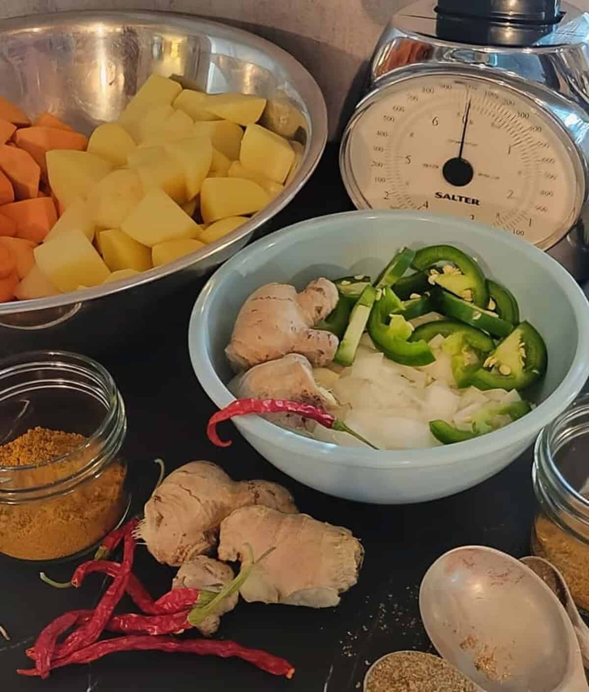 curry ingredients: chopped potato, sweet potato, whole ginger, sliced jalapeno, diced onion, curry powder, dried red chilies, coriander and cumin
