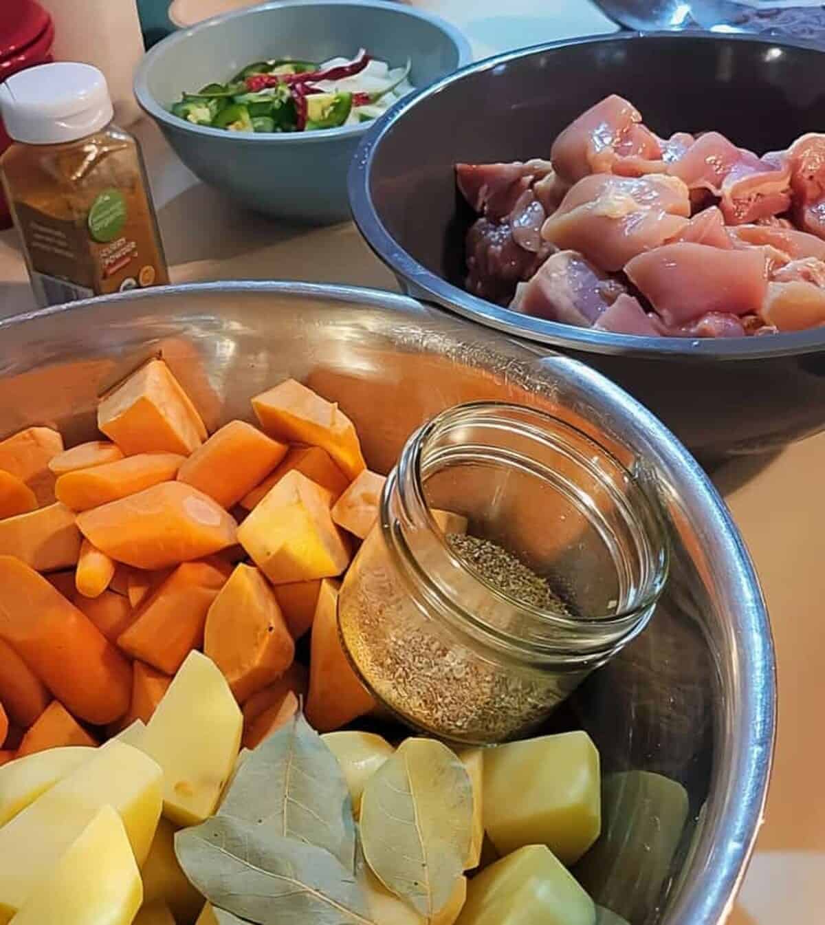 chopped and peeled sweet potatoes and yukon potatoes, bay leaves, dry coriander, jar of curry powder, diced raw chicken, sliced jalapeno, diced yellow onion, and dried red chilies