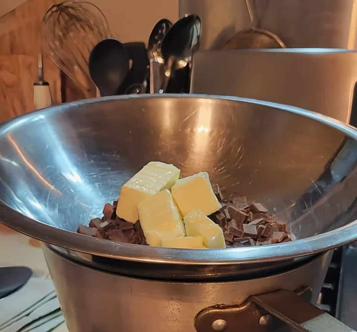 chopped chocolate and butter chunks shown in metal mixing bowl over sauce pan forming a double boiler
flourless chocolate torte