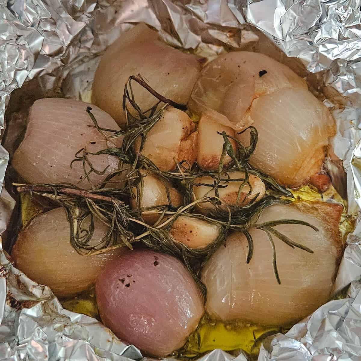 the finished roasted shallots, garlic, and rosemary in aluminum foil for the potato and shallot soup with crispy prosciutto