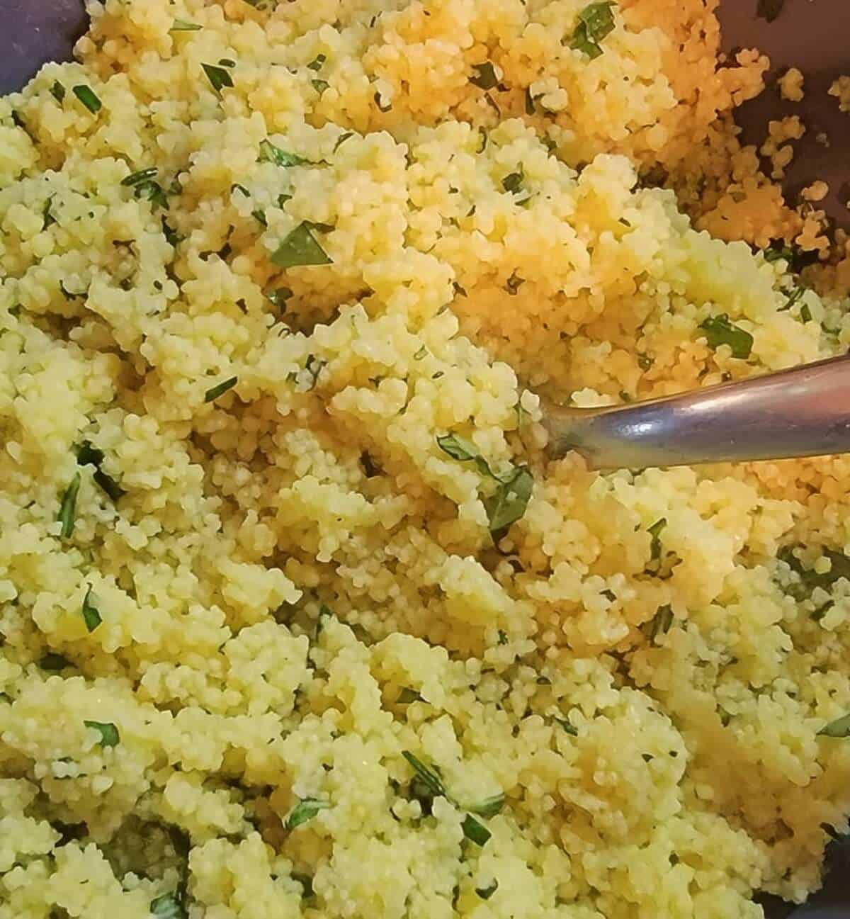 finished herb couscous being fluffed with a fork