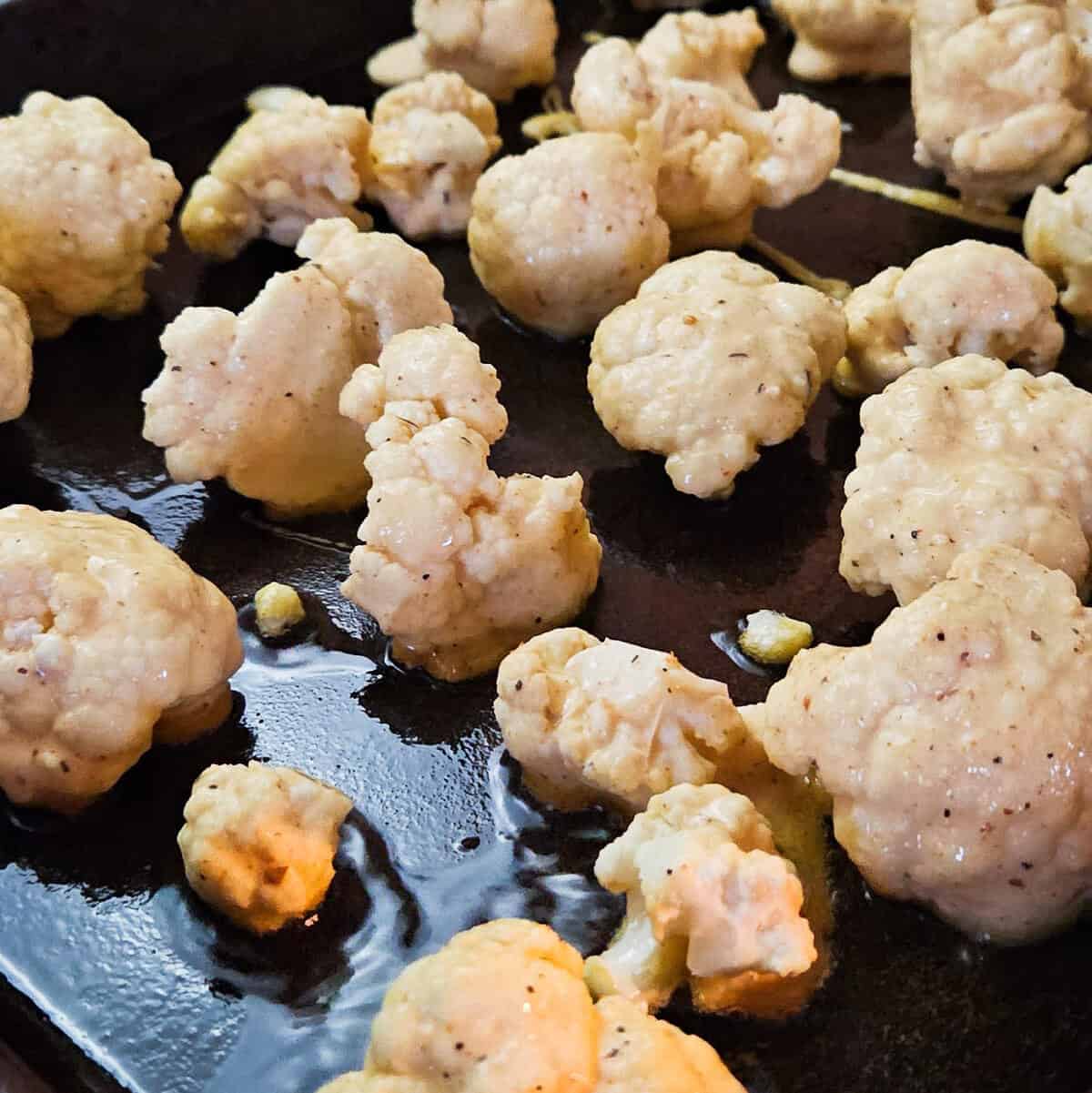 Crispy cauliflower bites batter and placed on a baking pan that is preheated with oil.