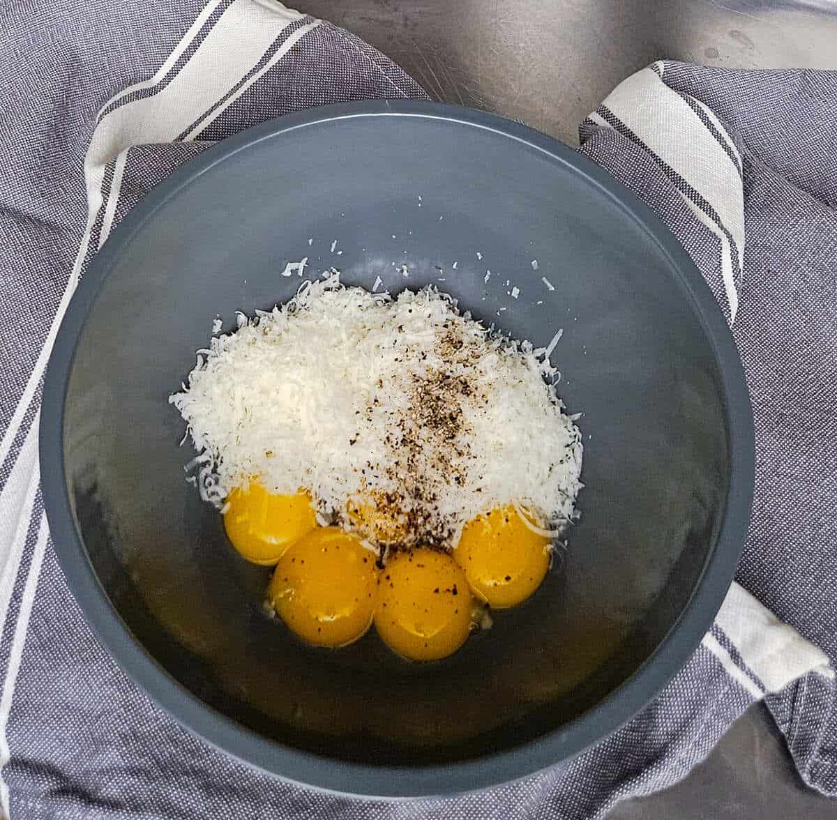 eggs, grated cheese, and black pepper in a bowl for the pasta carbonara with mushrooms