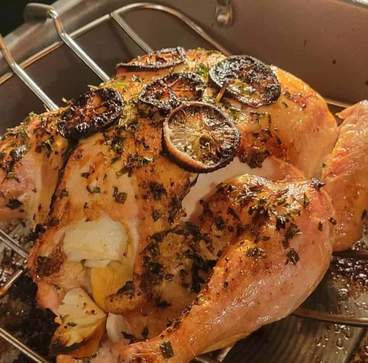 roasted chicken in pan, finished, with herbs and lemon slices