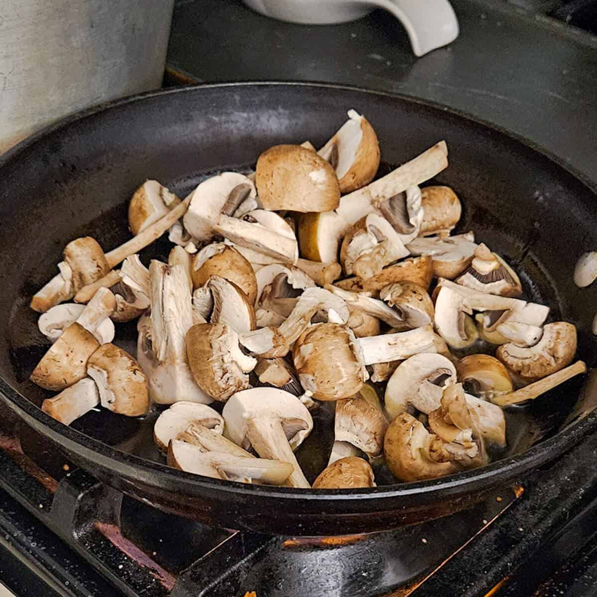 the quartered mushroom cooking in a pan for the pasta carbonara with mushrooms