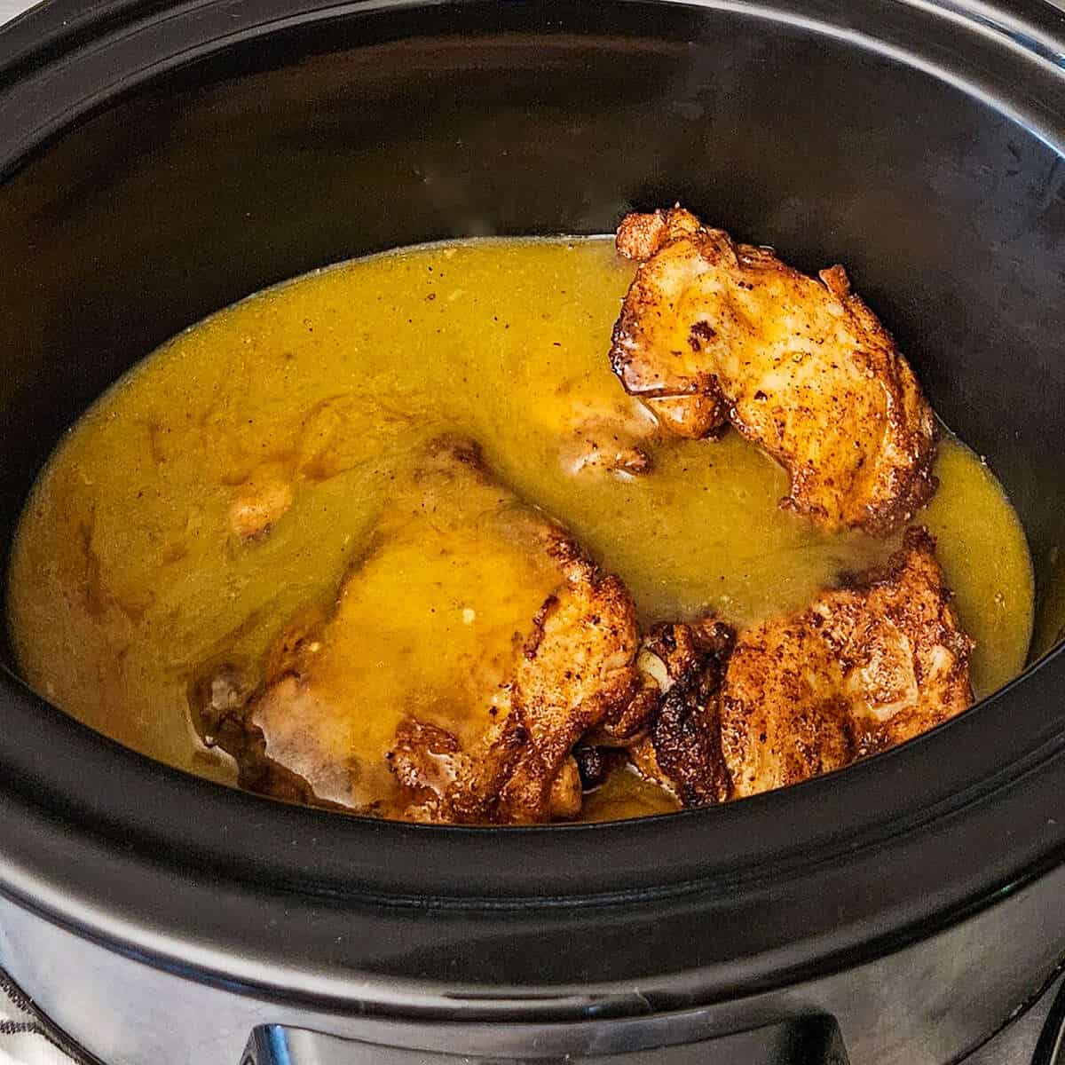 seared chicken and sauce in the crockpot for chicken enchilada casserole
