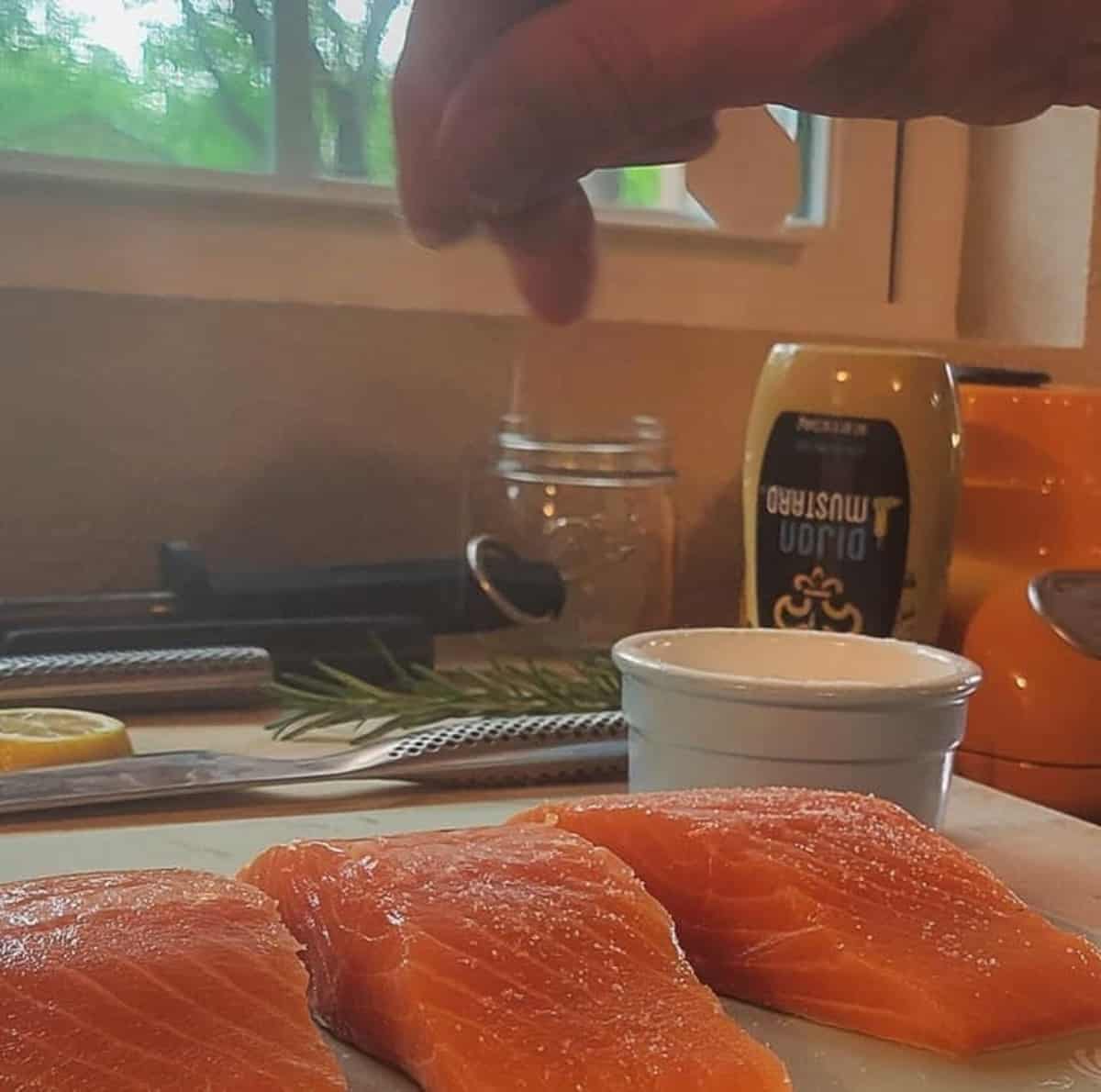 raw salmon portions being seasoned with salt