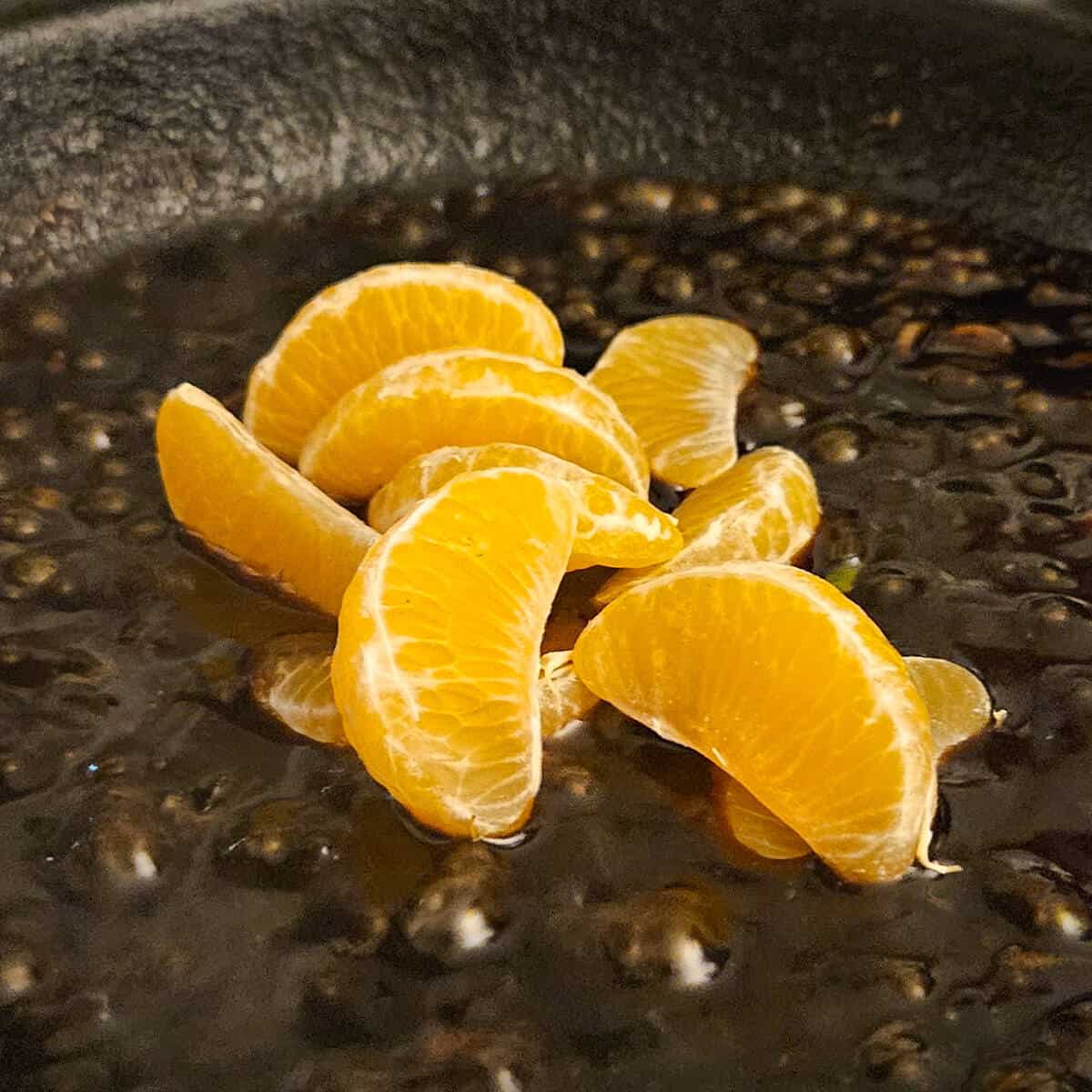 tangerine pieces being added to the pan for the cast iron seared pork tenderloin with tangerine ginger sauce