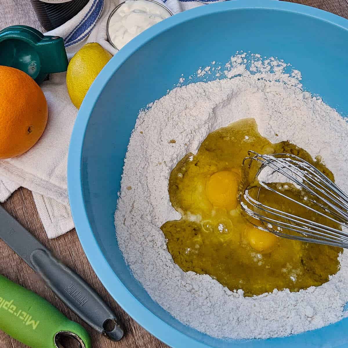 adding the eggs and olive oil to the dry ingredients for the gluten free olive oil cake