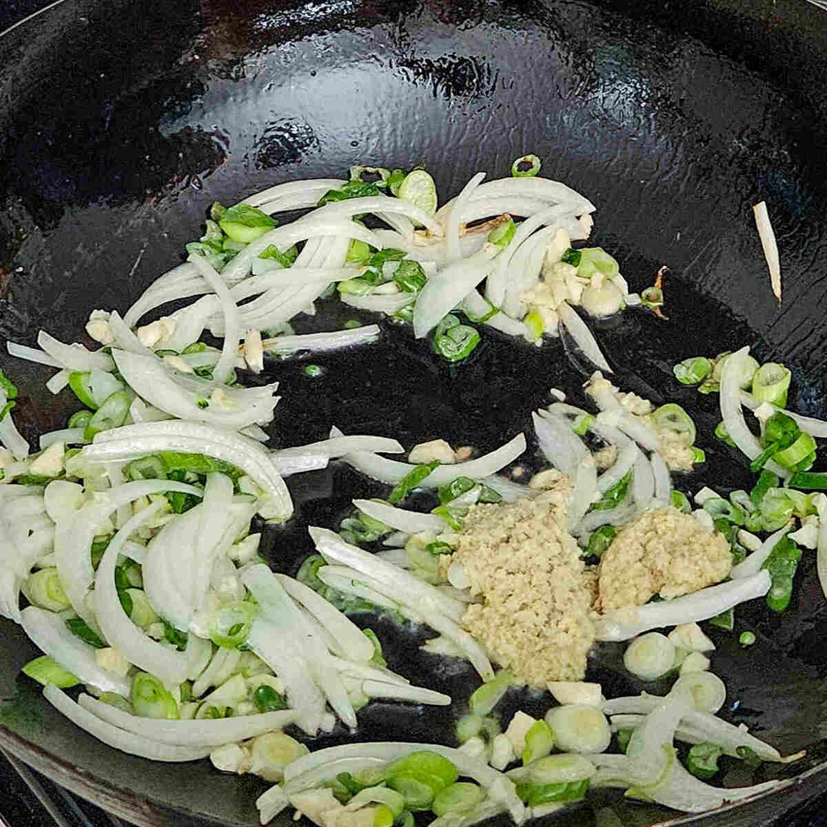 cooking the onions, garlic, and ginger in the wok for the easy Asian vegetable stir fry rice noodles recipe