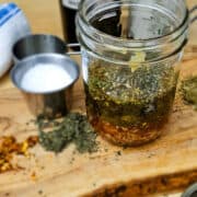 the ingredients for the Italian salad dressing in a mason jar with salt and extra dried herbs