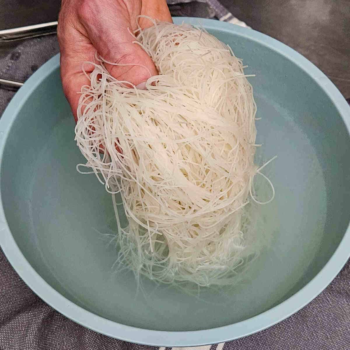 removing the softened rice noodles from the bowl of water, for the easy Asian vegetable stir fry rice noodles recipe