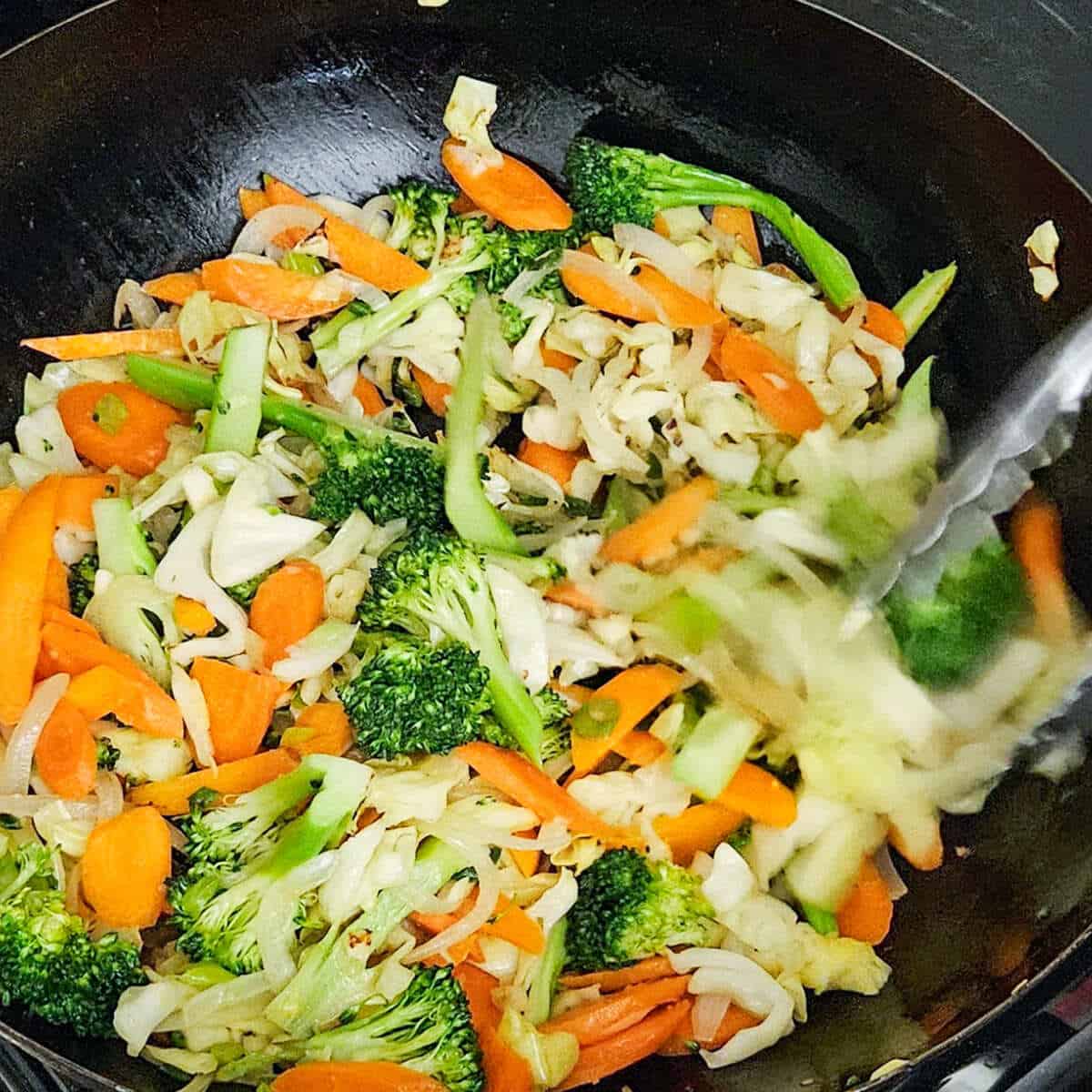 stir frying the vegetables in the wok for the easy Asian vegetable stir fry rice noodles recipe